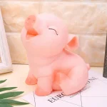 Hucha con forma de cerdito rosa sentado, con los ojos cerrados y expresión feliz, diseño decorativo sobre superficie clara con fondo interior.